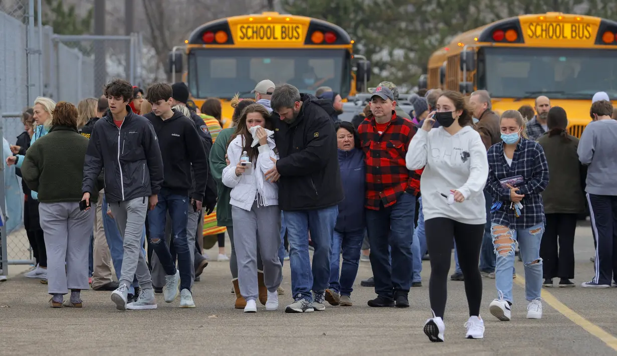Orang tua berjalan pergi dengan anak-anak mereka dari tempat parkir Meijer, di mana banyak siswa berkumpul menyusul situasi penembak aktif di Oxford High School di Oxford, Michigan (30/11/2021). Polisi telah menahan seorang tersangka penembak. (Eric Seals/Detroit Free Press via AP)