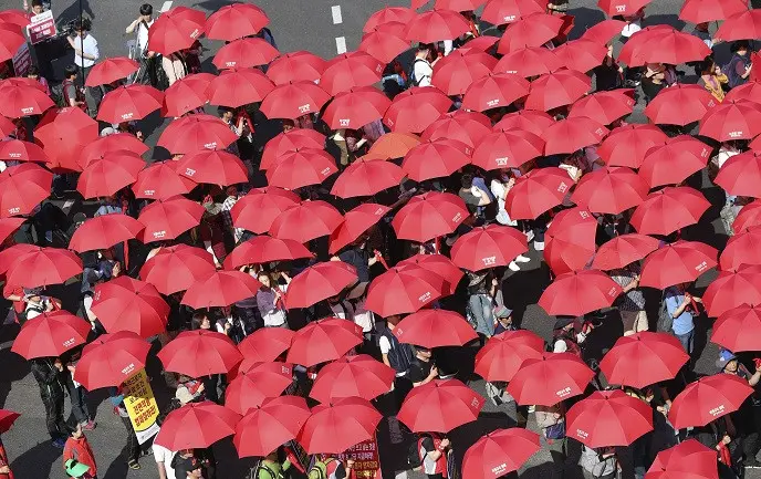 Peserta aksi May Day di Seoul, Korea Selatan, melakukan long march dengan membawa payung merah (AP)