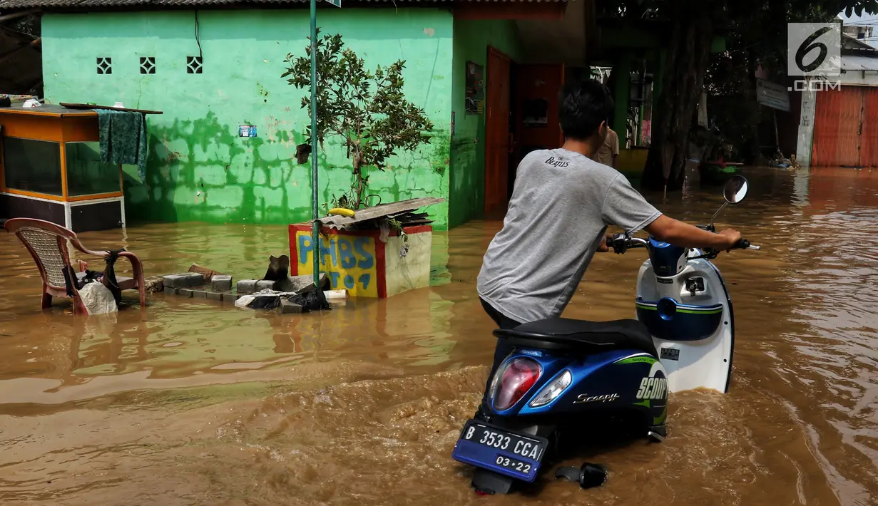 Warga melintasi banjir yang melanda kawasan bantaran kali Cisadane, Tangerang, Jumat (26/4). Banjir kiriman setinggi 2 meter sempat melanda kawasan akibat curah hujan yang tinggi di bogor membuat derasnya air mengalir jauh sampai ke tempat ini. (Liputan6.com/Johan Tallo)