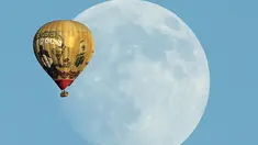 Sebuah balon udara terbang  melewati bulan yang terlihat dilangit California, Amerika Serikat 25 September 2015. (REUTERS/Mike Blake)