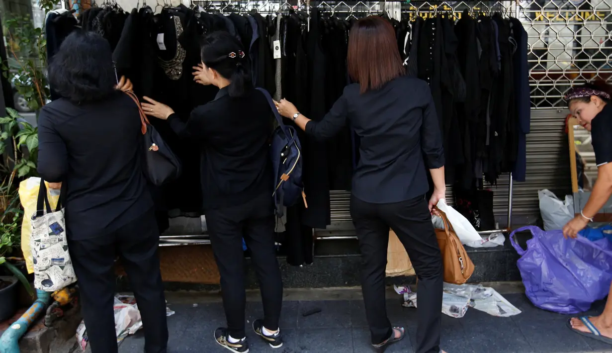 Warga membeli baju hitam untuk dikenakan selama masa berkabung atas wafatnya raja Bhumibol Adulyadej di Grand Palace di Bangkok, Thailand (17/10). Penduduk Bangkok mengenakan pakaian hitam sebagai tanda berduka kepergian raja mereka. (Reuters/Issei Kato)