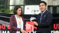 Presiden BEM KM Universitas Gadjah Mada (UGM) Obed Kresna Widyapratistha (kanan) menyerahkan kado buku merah kepada perwakilan Biro Humas KPK Brigita Simbolon pada aksi simpatik di Gedung KPK Jakarta, Senin (10/12). (Merdeka.com/Dwi Narwoko)