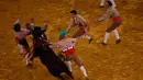 Para anggota Coruche Forcados berusaha menaklukkan seekor banteng yang mengamuk di arena Campo Pequeno, Lisbon, Portugal, (2/6/2016). Pertarungan ini merupakan pertunjukan tradisional yang telah lama ada di Portugal. (REUTERS/Rafael Marchante)