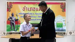 Salah seorang remaja, Mongkol Boonpiam menerima kartu identitas sebagai warga negara Thailand di distrik Mae Sai, Rabu (8/8). Korban gua Thailand tersebut selama ini hidup tanpa memiliki status kewarganegaraan (Chiang Rai Public Relations Office via AP)