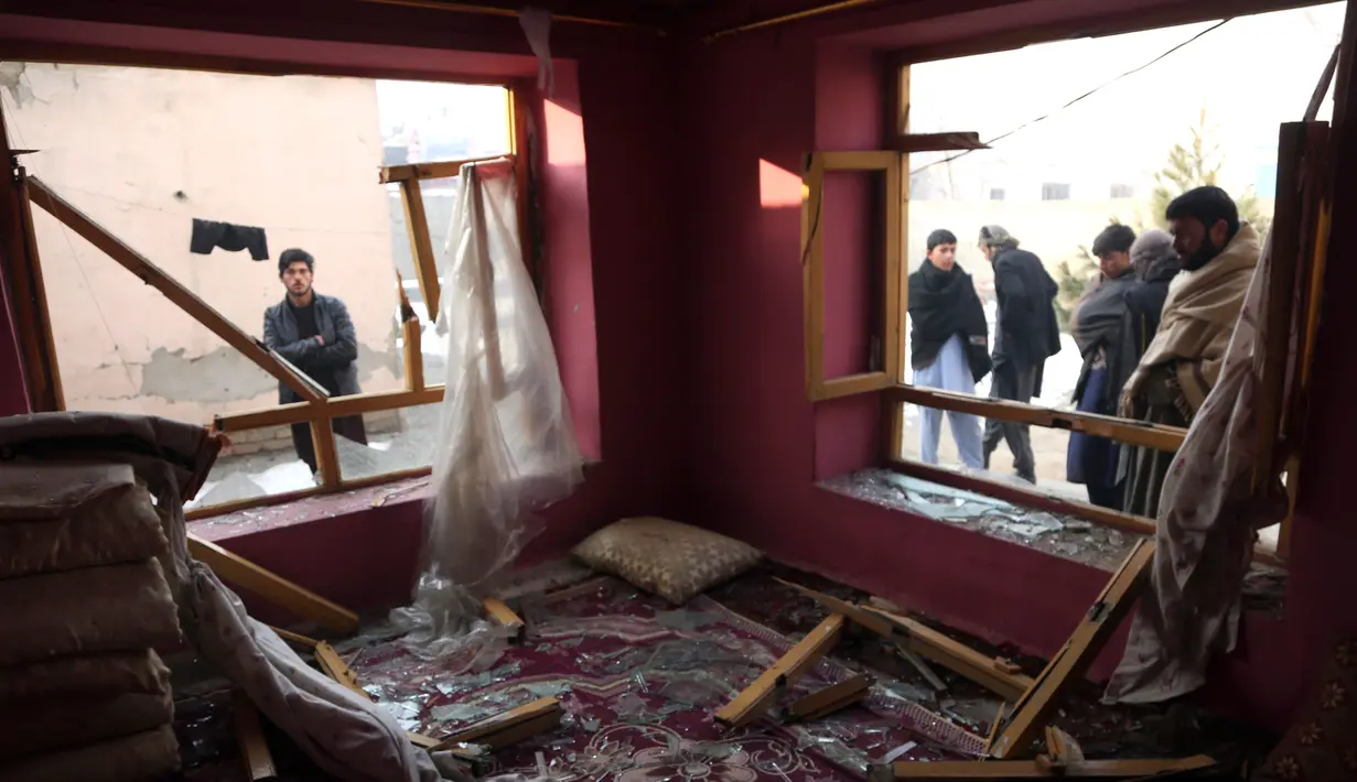 Penduduk desa berdiri di dekat sebuah rumah yang hancur setelah serangan di Kabul, Afghanistan (15/1). Empat orang tewas dan 113 orang lainnya terluka akibat ledakan yang terjadi di dekat kompleks asing tersebut. (AP Photo/Rahmat Gul)