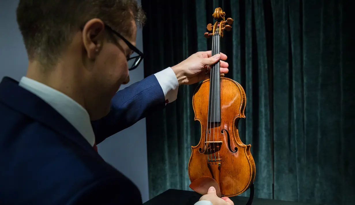 Perwakilan dari Sotheby Hong Kong memegang biola langka 1684 buatan Antonio Stradivari saat diperkenalkan di hadapan pers di Hong Kong (21/2). Pelelangan biola ini akan digelar pada 28 Maret 2017 mendatang di London. (AFP Photo / Isaac Lawrence)