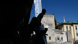 Penonton menyaksikan peserta melompat dari jembatan Mostar selama kompetisi menyelam tradisional ke 451 di Mostar, Bosnia, Minggu (30/7). Total 41 peserta dari Bosnia dan negara tetangga mengikuti kompetisi menyelam tahunan tersebut. (AP Photo/Amel Emric)