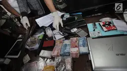 Sejumlah uang dan sebuah senjata api yang berhasil diamankan petugas saat penggerebekan di Kampung Ambon, Cengkareng, Jakarta, Rabu (24/1). Petugas juga berhasil mengamankan senjata api berikut amunisi, dan senjata tajam. (Liputan6.com/Arya Manggala)