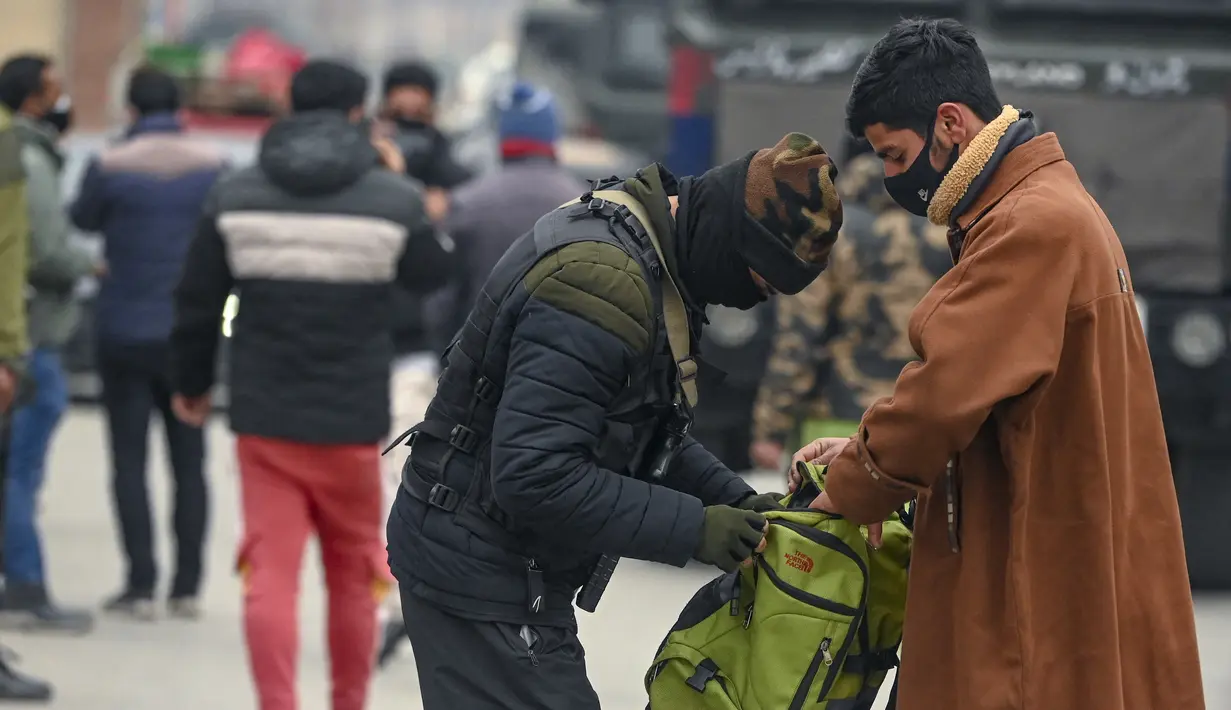 Personel Special Operation Group (SOG) menggeledah tas seseorang di sepanjang jalan selama pencarian acak pejalan kaki di Srinagar, kota terbesar di Kashmir, Jumat (21/1/2022). Peningkatan keamanan dilakukan menjelang Hari Republik India pada 26 Januari mendatang. (TAUSEEF MUSTAFA / AFP)