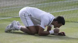 Setelah bertanding selama dua setengah jam, petenis Serbia itu meluapkan emosinya dengan berlutut dan makan sejumput rumput lapangan di depan 15.000 penonton, termasuk para selebriti, London, Minggu (6/7/14). (REUTERS/Suzanne Plunkett)