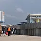Wisatawan berjalan di dekat tanggul laut di Pelabuhan Kali Adem, Muara Angke, Jakarta, Selasa (12/2). Pembangunan tanggul laut tersebut merupakan bagian dari program Pengembangan Terpadu Pesisir Ibukota Negara atau NCICD. (Merdeka.com/Iqbal S. Nugroho)