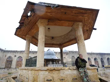Seorang anggota pasukan Presiden Suriah Bashar al-Assad berdiri di salah satu bangunan yang berada di kompleks Masjid Umayyad, Aleppo di Suriah, 13 Desember 2016. Masjid ini menjadi salah satu masjid tertua di dunia. (REUTERS/Omar Sanadiki)
