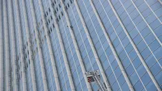 Tangga dinas pemadam kebakaran Korea Selatan berusaha mendekati pemanjat gedung, Alain Robert di Menara Lotte World, Seoul (6/6). Alain Robert dicegat dan diamankan petugas saat berusaha menaklukan Menara Lotte World. (AFP/Ed Jones)