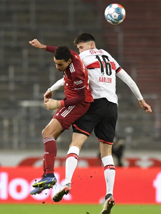 Gelandang Bayern Munchen Jamal Musiala (kiri) dan bek VfB Stuttgart Atakan Karazor melompat saat berebut bola pada lanjutan Liga Jerman di Mercedes-Benz Arena, Rabu (15/12/2021) dinihari WIB. Bayern Munchen sukses melumat VfB Stuttgart dengan skor 5-0. (Thomas KIENZLE/AFP)
