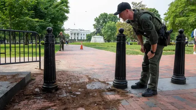 Seorang polisi taman AS memeriksa penghalang keamanan untuk kerusakan di taman Lafayette Square dekat Gedung Putih. [Alex Brandon/AP]