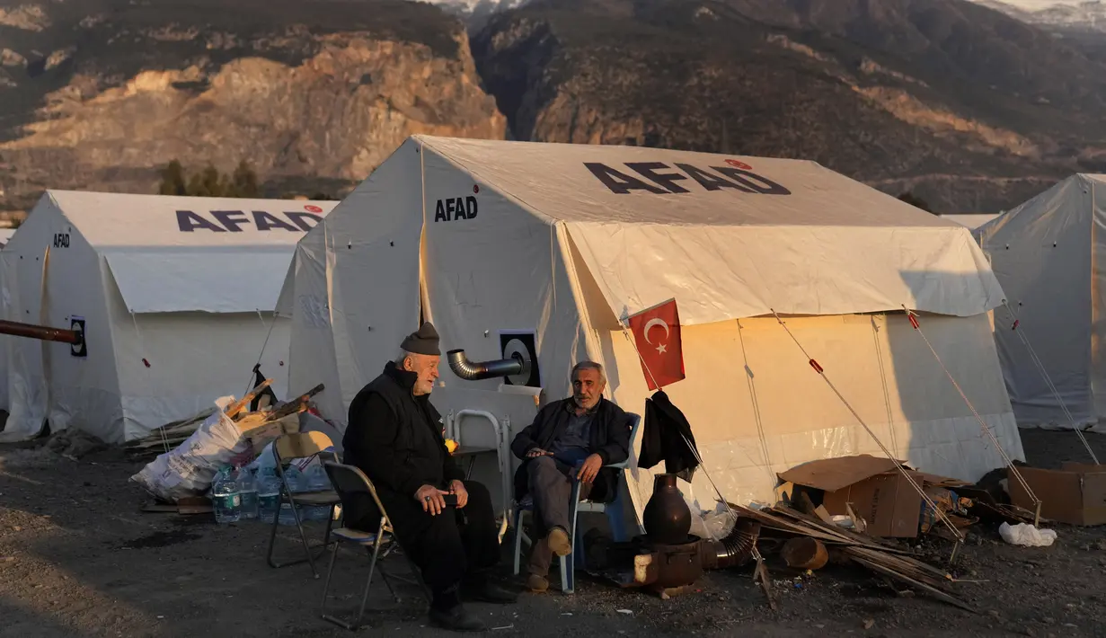 Orang-orang yang kehilangan rumah akibat gempa dahsyat, duduk di luar tenda mereka di kamp darurat, di kota Iskenderun, Turki selatan, Selasa, 14 Februari 2023. Ribuan orang kehilangan tempat tinggal akibat gempa bumi dahsyat yang melanda Turki dan Suriah seminggu yang lalu. (AP Photo/Hussein Malla)