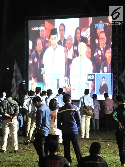 Para pendukung Capres dan Cawapres nomor urut 01 dan 02 saat nonton bareng Debat Perdana Pilpres di kawasan Gedung Bidakara, Jakarta, Kamis (17/1). Mereka menonton dengan layar tancap yang disediakan warga sekitar. (merdeka.com/Iqbal S Nugroho)