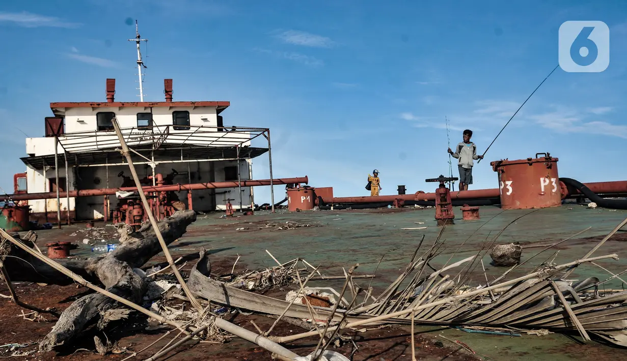 Warga bersama anaknya saat memancing dari atas sebuah kapal karam di pesisir Kali Adem, Muara Angke, Jakarta, Minggu (27/12/2020). Sebuah kapal yang telah karam selama bertahun-tahun tersebut dimanfaatkan sebagai tempat memancing meskipun berisiko membahayakan keselamatan (merdeka.com/Iqbal Nugroho)