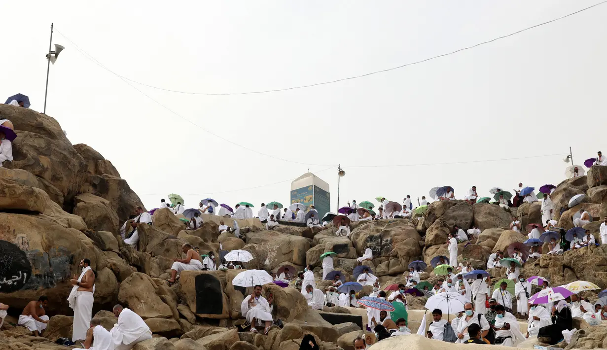 <p>Jemaah haji berkumpul di sekitar Jabal al-Rahma (Gunung Rahmat) saat menunaikan prosesi wukuf di Padang Arafah, tenggara Kota Suci Mekah, Arab Saudi, Senin (19/7/2021). Wukuf di Padang Arafah dua tahun terakhir berada dalam pembatasan karena pandemi corona virus COVID-19. (FAYEZ NURELDINE/AFP)</p>