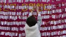 Seorang wanita menggantungkan kertas untuk mendoakan keberhasilan anaknya dalam ujian masuk perguruan tinggi di kuil Buddha Jogyesa, Seoul, Rabu (17/11/2021). Sekitar 500.000 siswa SMA di Korea Selatan diperkirakan akan mengikuti Tes Kemampuan Skolastik Perguruan Tinggi. (AP Photo/Ahn Young-joon)