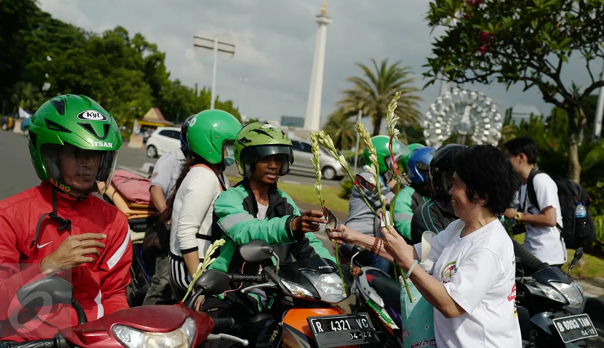 Gemabudhi membagikan bunga kepada pengguna jalan di depan Istana Negara, Jakarta, Sabtu (6/1). Aksi membagikan 2.561 tangkai bunga sedap malam tersebut dilakukan dalam rangka memperingati Hari Raya Trisuci Waisak 2561 B.E. (Liputan6.com/Immanuel Antonius)
