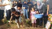 Ade Jigo dan kedua anaknya di pemakaman istrinya, Meyuza Zainal Abidin (Dok. Keluarga Ade Jigo / Nefri Inge)