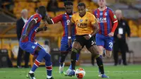 Gelandang Wolverhampton Wanderers, Adama Traore, berebut bola dengan gelandang Crystal Palace, Jeffrey Schlupp, pada laga lanjutan Premier League di Molineux Stadium, Selasa (21/7/2020) dini hari WIB. Wolves menang 2-0 atas Crystal Palace. (AFP/Martin Rickett/pool)