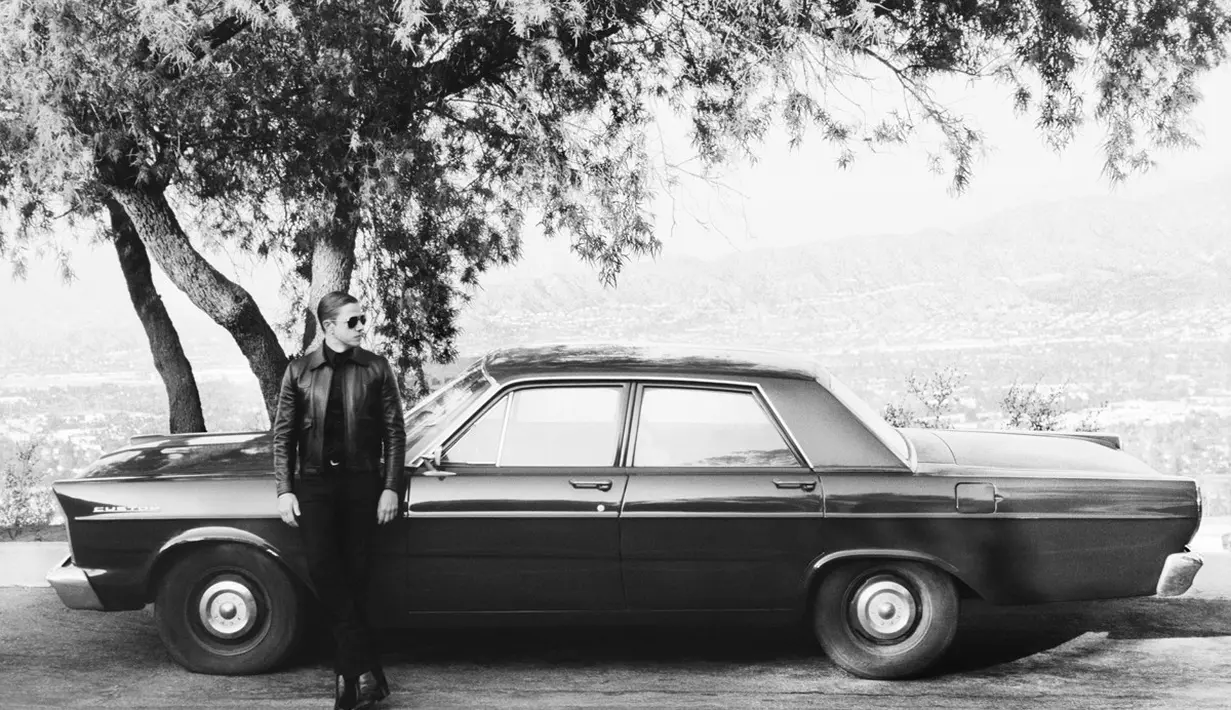 Pesona tampannya semakin terlihat dengan jaket kulit dan kemeja hitam [Celine Homme]