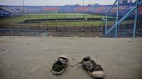 Sepasang sepatu kets terinjak-injak di tribun Stadion Kanjuruhan menyusul tragedi mengeneskan usai pertandingan Arema FC melawan Persebaya di Stadion Kanjuruhan, Malang, Jawa Timur, Indonesia, Minggu (02/10/2022). Setidaknya lebih dari 100 orang tewas ketika penggemar tuan rumah yang marah menyerbu lapangan dan polisi menanggapi dengan gas air mata yang memicu desak-desakan. (AP/Hendra Permana)