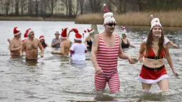 Dua anggota klub renang "Berliner Seehunde" (Berlin Seals) berjalan keluar dari Danau Orankesee di Berlin, Minggu (25/12). Kegiatan yang sudah menjadi tradisi ini merupakan bagian dari perayaan tradisional Natal bagi warga Berlin. (Tobias SCHWARZ / AFP)