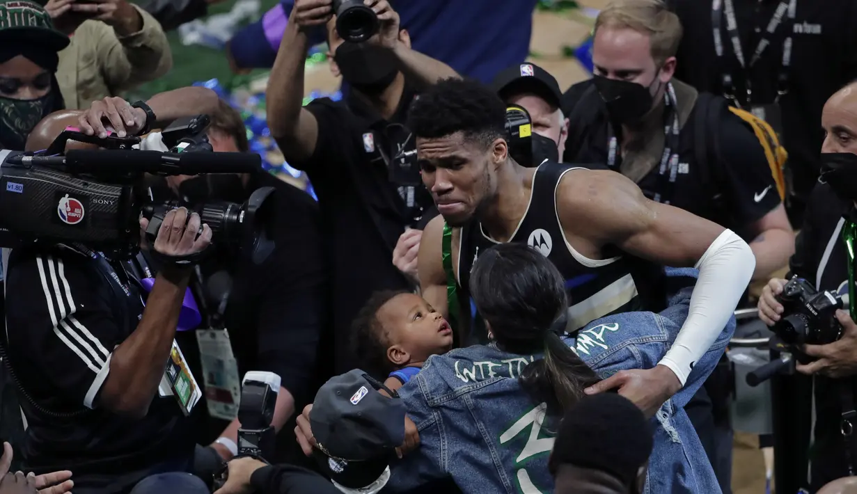 Pebasket Milwaukee Bucks Giannis Antetokounmpo memeluk pacarnya Mariah Riddlesprigger dan putranya Liam setelah mengalahkan Phoenix Suns di Game 6 Final NBA bola basket di Milwaukee, Selasa (20/7/2021). Bucks resmi menjadi juara NBA musim ini, atau yang pertama sejak 1971. (AP Photo/Aaron Gash)