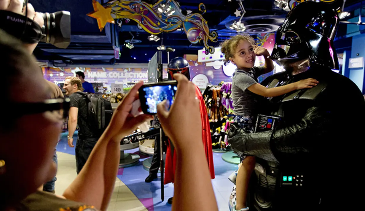 Pria berkostum Darth Vader berpose dengan seorang anak didalam toko mainan di Times Square,  New York, Jumat (4/9/2015). Acara ini dilakukan untuk menarik minat warga untuk menonton dan membeli barang yang berbau Star Wars. (REUTERS/Carlo Allegri)