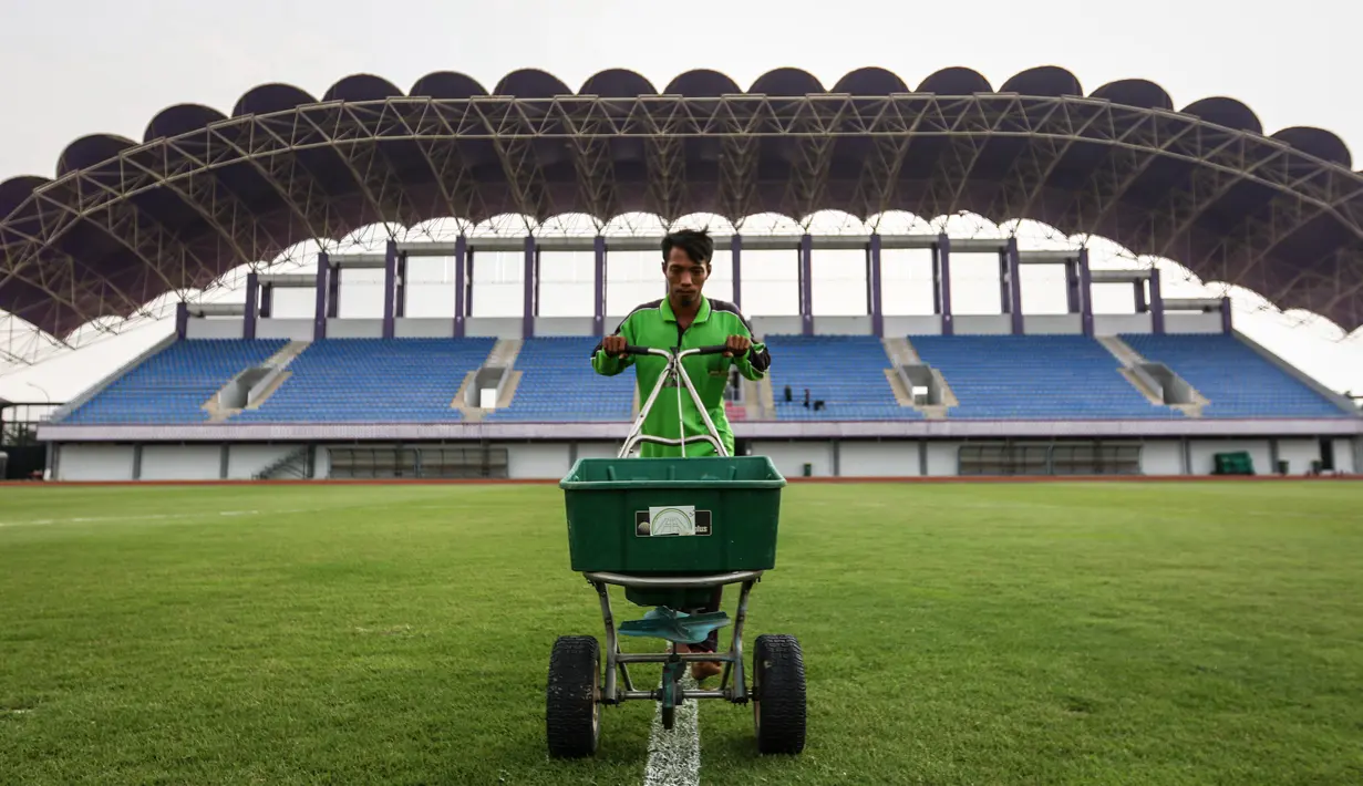 Pekerja sedang melakukan pemupukan rumput di Stadion Indomilk Arena, Tangerang pada Rabu (25/08/2021) sore WIB. Hal tersebut merupakan salah satu bentuk perawatan dan persiapan stadion untuk menyambut kompetisi BRI Liga 1 yang akan segera bergulir. (Foto: Bola.com/Bagaskara Lazuardi)