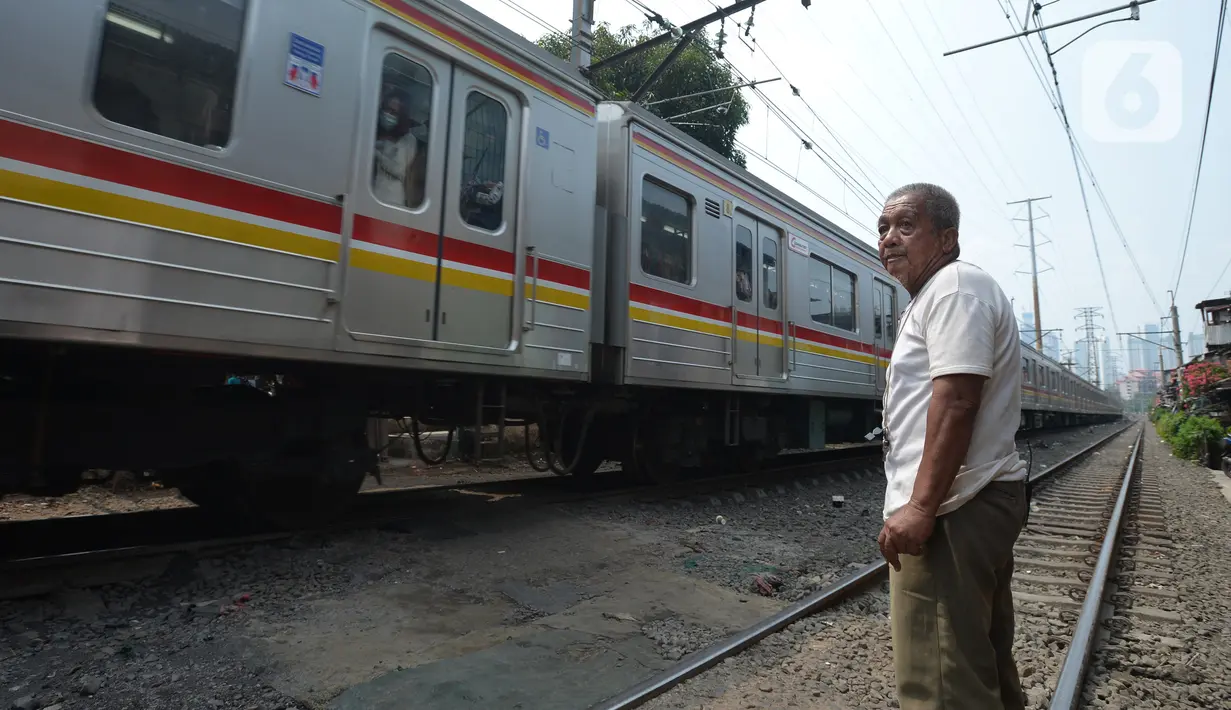 Penjaga perlintasan kereta api tanpa palang pintu, Wandi, menjaga perlintasan di Kawasan Petamburan, Jakarta, Jumat (4/6/2021). Sudah 10 tahun, Bapak Wandi menjaga palang pintu perlintasan kereta api yang kerap dilintasi oleh pengguna jalan untuk menyeberang. (merdeka.com/Imam Buhori)