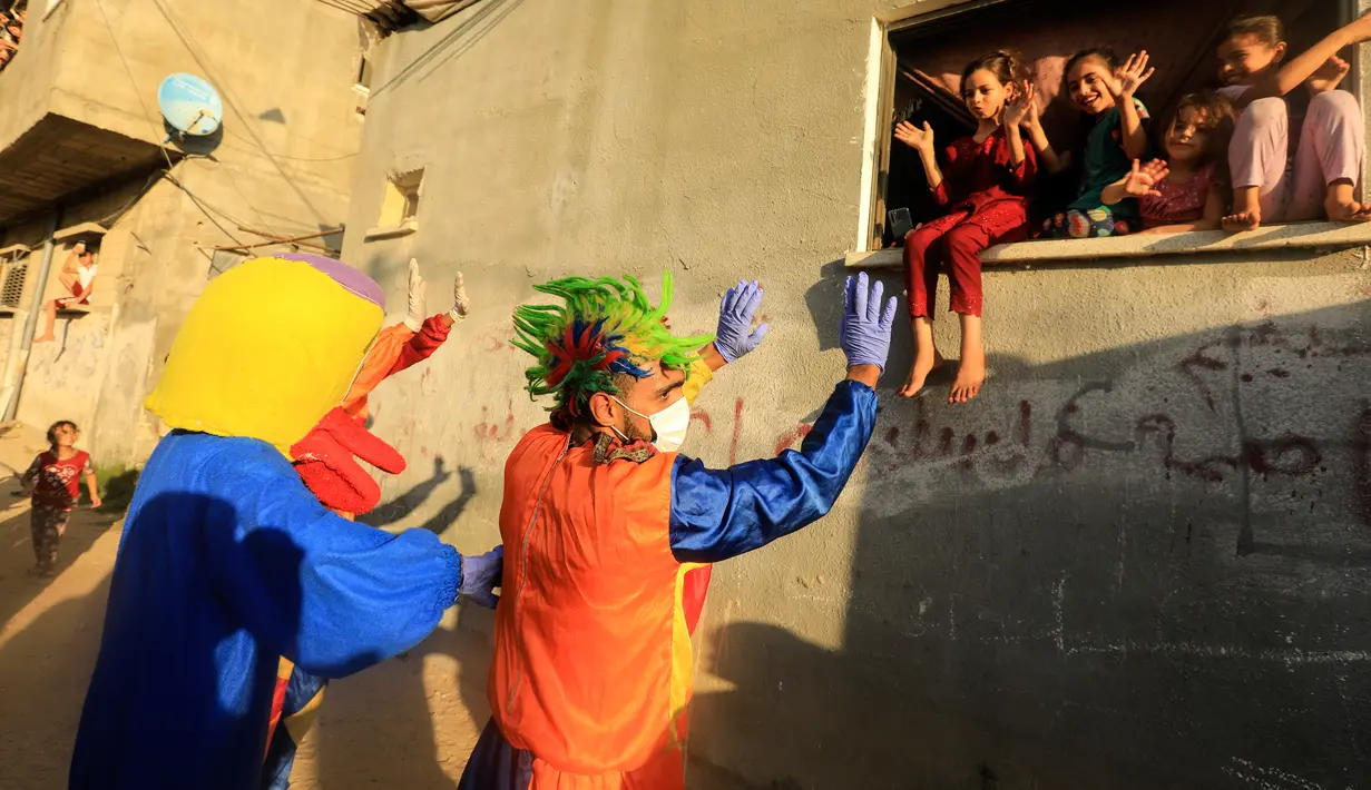 Badut dan seseorang yang mengenakan kostum bebek menghibur anak-anak Palestina, di tengah lockdown yang diberlakukan oleh otoritas setempat menyusul lonjakan kasus virus corona, di Khan Younis, Jalur Gaza selatan pada Rabu (2/9/2020). (MAHMUD HAMS/AFP)