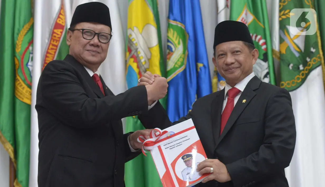 Menteri Dalam Negeri Tito Karnavian (kanan) menerima buku dari pejabat lama Tjahjo Kumolo saat  acara serah terima jabatan di Kantor Kemendagri, Jakarta, Rabu (23/10/2019). Presiden Jokowi resmi melantik Tito Karnavian menjadi mendagri dalam jajaran Kabinet Indonesia Maju. (merdeka.com/Imam Buhori)