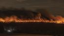 Api berkobar di sepanjang bagian bawah Pilot Mountain di North Carolina, AS (29/11/2021). Kebakaran yang dilaporkan telah dimulai Sabtu malam, telah membakar lebih dari 500 hektar pada Senin malam.  (Walt Unks/The Winston-Salem Journal via AP)