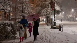 Pejalan kaki melintas saat salju mulai turun di Manhattan, New York, Kamis (15/11). Layanan Cuaca Nasional memprediksi hujan salju pertama pada awal musim dingin itu akan mencapai ketebalan 2-4 inci. (Angela Weiss / AFP)