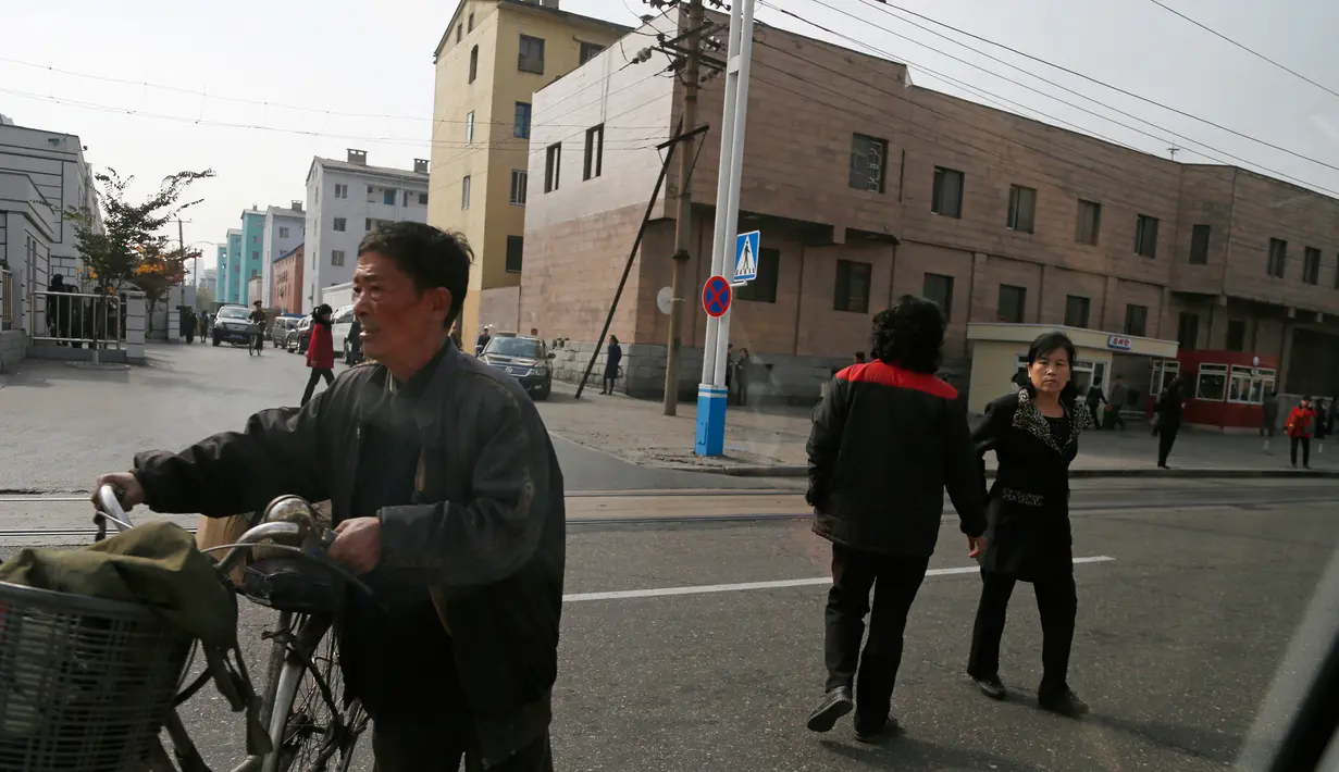 Orang-orang menyeberang jalan dengan latar bangunan tempat tinggal di Pyongyang, Korea Utara (22/10). (AP Photo / Dita Alangkara)