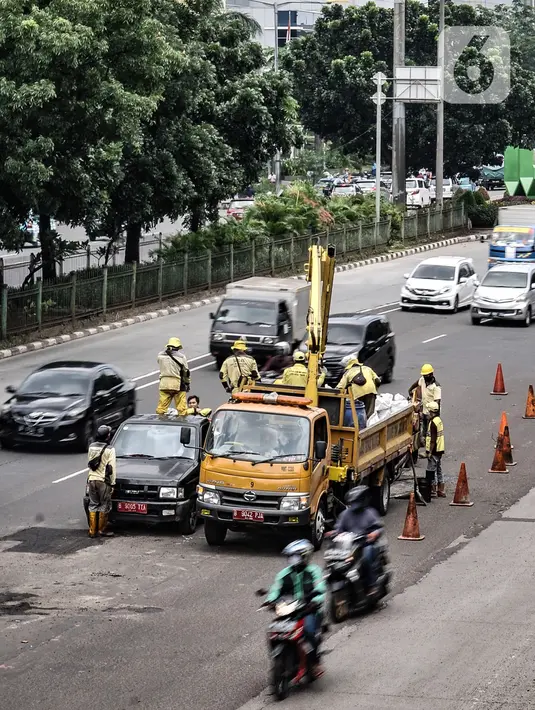 Kendaraan melintasi perbaikan jalan berlubang di Jalan DI Panjaitan, Cawang, Jakarta, Senin (25/1/2021). Perbaikan jalan rusak dan berlubang akibat sering tergenang banjir di kawasan tersebut dilakukan untuk mengantisipasi terjadinya kecelakaan pengendara. (merdeka.com/Iqbal S Nugroho)
