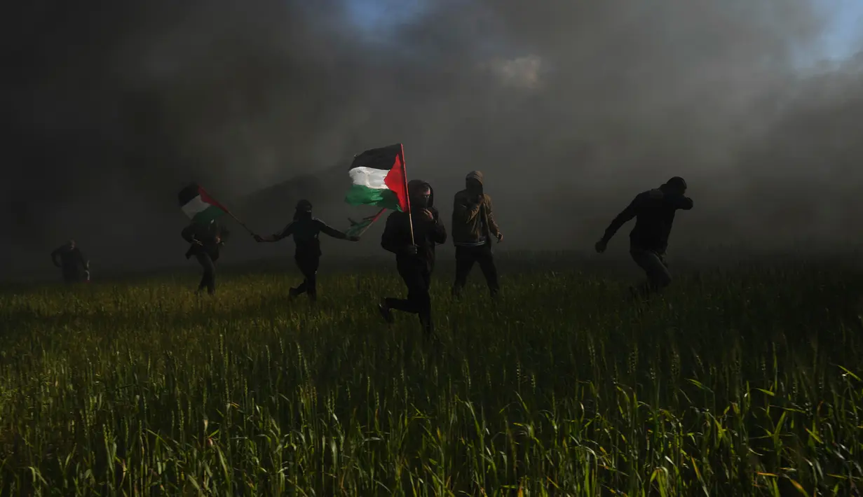 Warga Palestina mengibarkan bendera nasional saat protes terhadap serangan militer Israel ke Kota Nablus, Tepi Barat, di sepanjang pagar perbatasan dengan Israel di sebelah timur Kota Gaza, 22 Februari 2023. Para pejabat Palestina mengatakan sejumlah warga Palestina telah terbunuh dan lebih dari seratus orang terluka dalam serangan tentara Israel yang jarang terjadi di Tepi Barat. (AP Photo/Adel Hana)