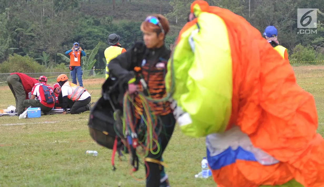 Petugas mengevakuasi atlet paralayang putri asal Malaysia Sharifah Nadiah Wafa saat bertanding pada nomor ketepatan mendarat Asian Games 2018, Bogor (21/8). Sharifah diduga mengalami cedera bagian pinggul kaki kanan ke bawah. (Merdeka.com/Arie Basuki)