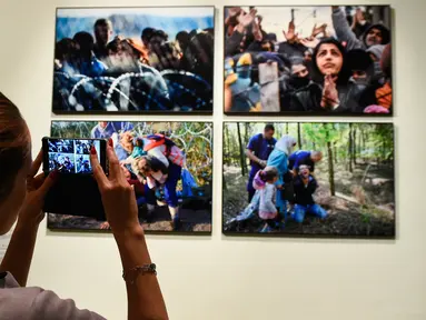 Pengunjung mengambil foto saat pameran karya fotografer Agence France-Presse (AFP) mengenai krisis migrasi di Eropa di pusat seni Bozar di Brussels (3/5). Pameran ini berjudul "Puting a Face on the Invisibles. (AFP Photo/John Thys)