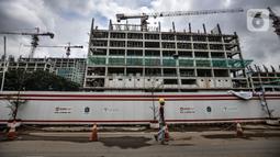 Pekerja melintas di depan proyek pembangunan rumah susun sewa (Rusunawa) PIK Pulogadung, Jakarta, Kamis (25/2/2021). Pemprov DKI Jakarta menargetkan proyek pembangunan 10 rusun rampung pada tahun 2021. (merdeka.com/Iqbal S. Nugroho)