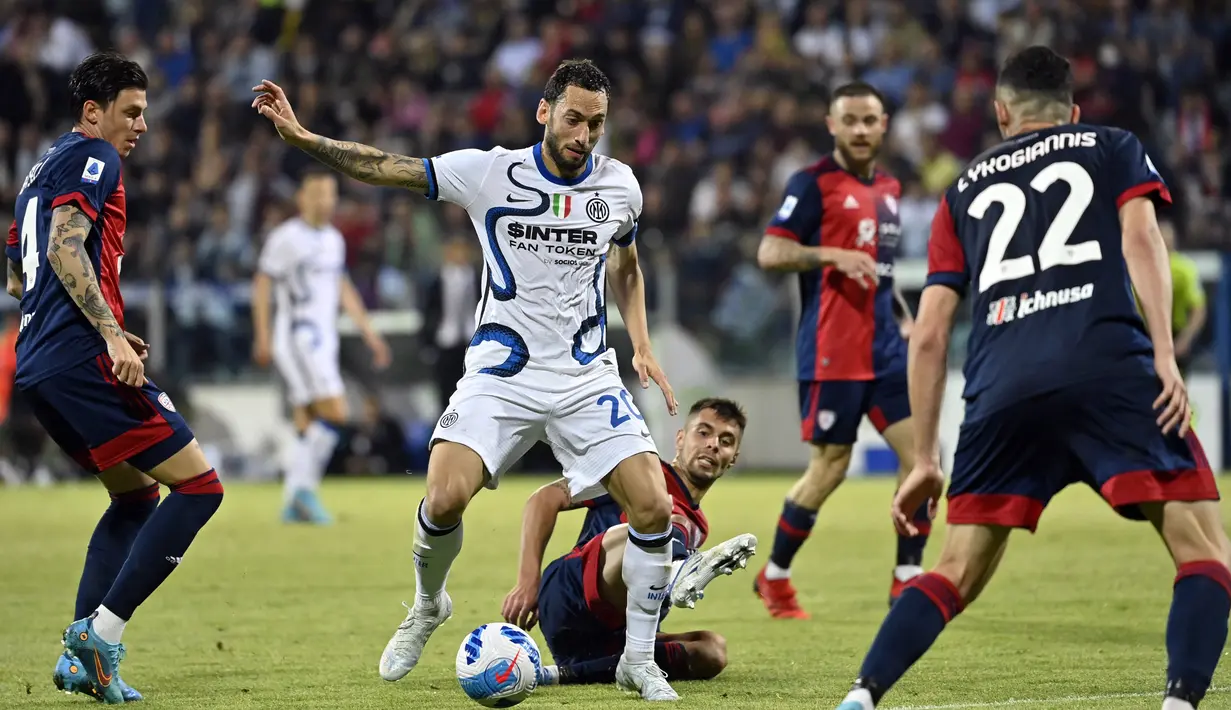 Pemain Inter Milan Hakan Calhanoglu berebut bola dengan pemain Cagliari Daniele Baselli dan Charis Lykogiannis pada pertandingan sepak bola Liga Italia di Sardegna Arena, Cagliari, Italia, 15 Mei 2022. Inter Milan menang 3-1. (Alberto PIZZOLI/AFP)