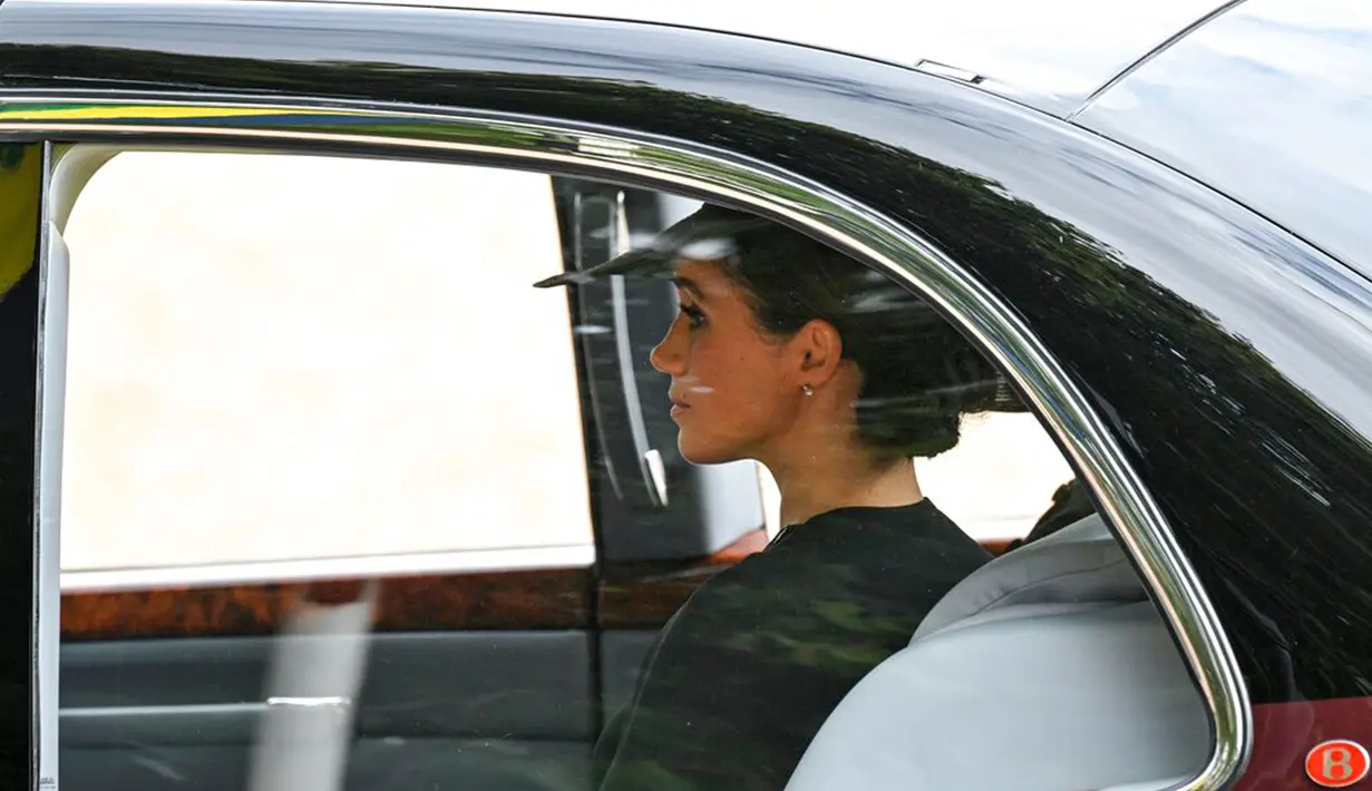 Duchess of Sussex Meghan Markle duduk dalam mobil saat prosesi pemakaman Ratu Elizabeth II dari Westminster Abbey ke Wellington Arch di London, Inggris, 19 September 2022. Meghan Markle hadir dengan mengenakan gaun hitam dengan cape (jubah) dan dipasangkan dengan topi bertepi lebar. (Loic Venance/Pool Photo via AP)