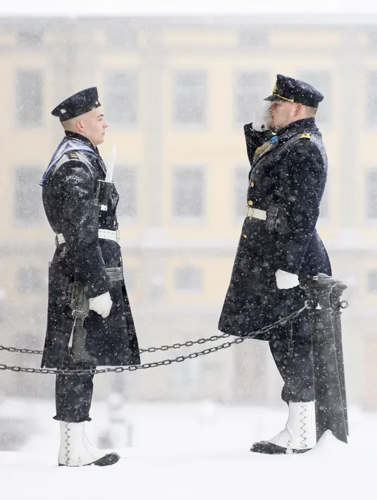 Penjaga kerajaan berdiri saat salju turun di luar Royal Castle di Stockholm, Swedia (28/1/2021). Ibu kota Swedia mungkin mendapatkan salju sepanjang hari. (Henrik Montgomery/TT via AP)
