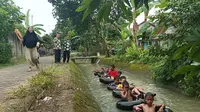 Tangkapan layar video anak-anak sedang bermain ala river tubing di aliran irigasi Kabupaten Blora, Jawa Tengah. (Liputan6.com/ Ahmad Adirin)