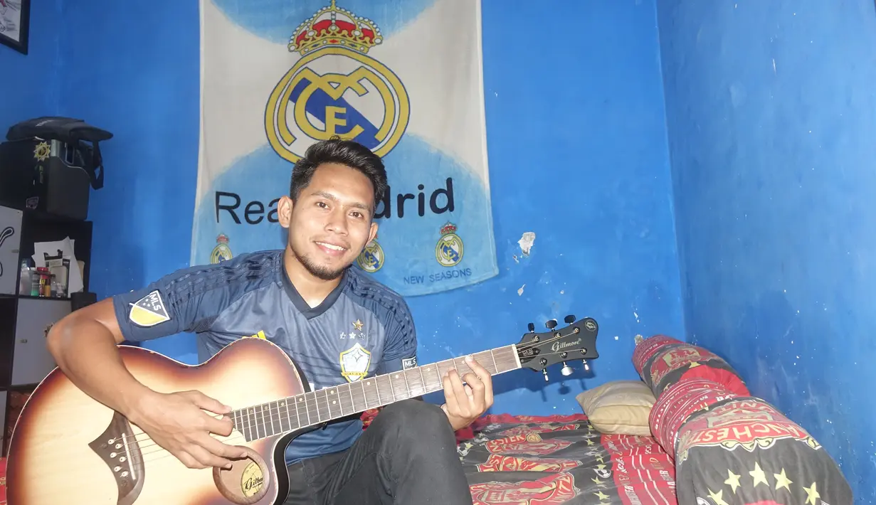 Andik Vermansah bersantai dalam kamarnya di rumah orang tuanya yang penuh dengan atribut Real Madrid dan Manchester United. (Bola.com/Zaidan Nazarul)