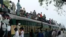 Sejumlah penumpang duduk di atas atap kereta saat mudik menuju kampung halaman untuk merayakan Idul Adha di Lahore, Pakistan, Sabtu (10/8/2019). Umat Islam di seluruh dunia merayakan Idul Adha yang identik dengan tradisi berkurban. (AP Photo/K.M. Chaudary)